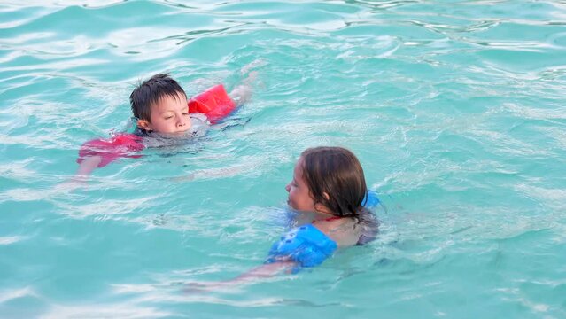 Ni&ntilde;os amigos hermanos rubios latinos jugando divertidos nadando en el veranos en una alberca en agua salpicando y disfrutando de una tarde soleada al aire libre 