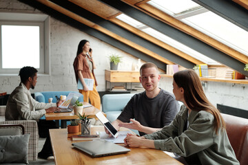 Confident young male employee pointing at tablet screen during explanation of online data to female colleague in coworking space - Powered by Adobe