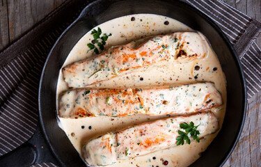 Cooked salmon fish with cream sauce in frying pan