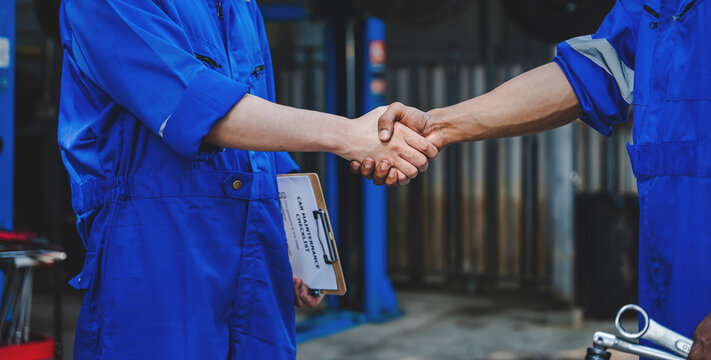 Auto mechanic handshake showing success collaboration of mechanics Check and maintain the engine for customers.