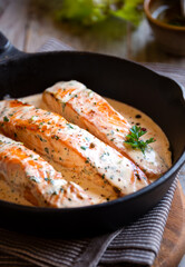 Cooked salmon fish with cream sauce in frying pan