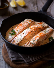 Cooked salmon fish with cream sauce in frying pan