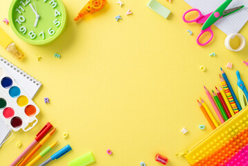 Explore magic of early education with this top-down perspective: delightful collection of colorful school supplies on isolated yellow backdrop, offering empty circle for text or promotional content