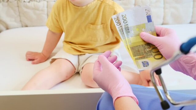 After the payment, the nurse counted the euros cash that was handed to her by the woman who brought in the baby for a medical exam. Kid aged about two years (one year eleven months)