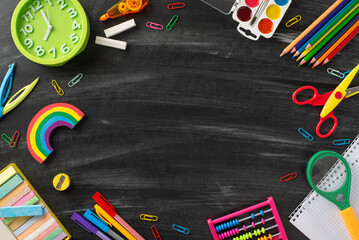 Embark on a captivating learning adventure with this top-down snapshot: a vivid array of child stationery on blackboard background, providing copyspace for text or promotional material