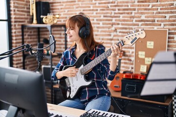 Young woman musician singing song playing electric guitar at music studio