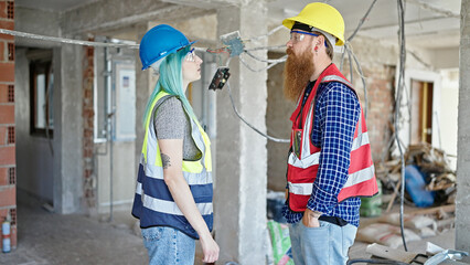Man and woman builders standing with relaxed expression working at construction site
