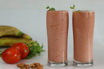 Tomato banana smoothie. A healthy drink made of ripe tomatoes and frozen bananas in almond milk served in a long glass with fresh mint leaves