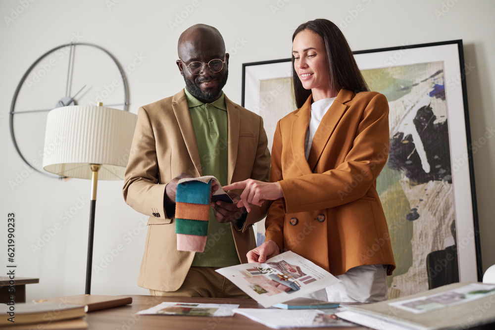Poster two young creative designers choosing color and textile from sample collection while working over de