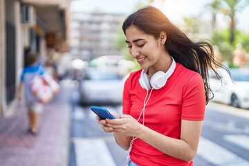 Young hispanic girl smiling confident using smartphone at street