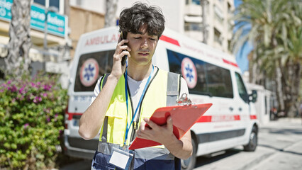 Young hispanic man nurse talking on smartphone standing by ambulance at street © Krakenimages.com