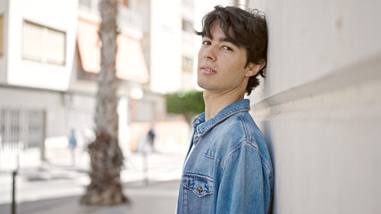 Young hispanic man standing with serious expression at university