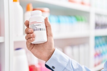 Young hispanic man customer holding pills bottle at street