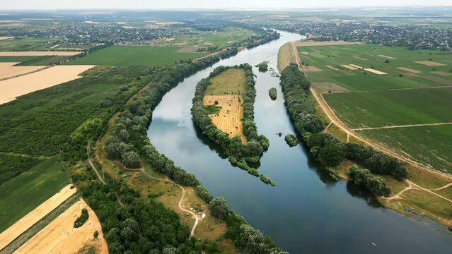 Aerial drone view of nature in Moldova. Dniester river with lush trees along it, villages in the distance and fields around