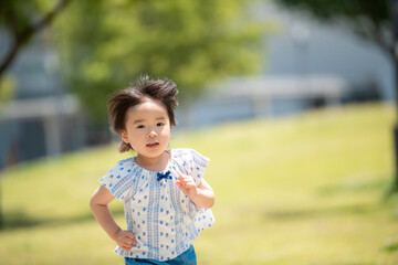 新緑の公園で遊ぶ3歳の女の子