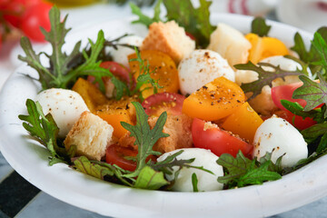 Tuscan Panzanella. Cherry Tomatoes salad with arugula, basil, mozzarella and bread crackers on white bowl. Traditional italian salad. Mediterranean healthy food and cuisine.