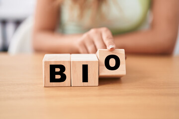 Fototapeta premium Young woman holding cubes with bio word on the table
