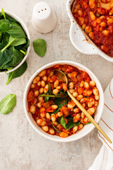 Healthy breakfasts and lunches, stewed white beans with carrots, onions and tomatoes with spinach leaves, a bowl of beans and spinach
