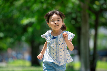 新緑の公園で遊ぶ5歳の女の子