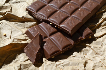 broken chocolate bars lie on brown paper