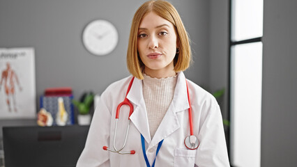 Young blonde woman doctor standing with serious expression at clinic