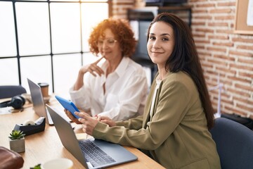 Two women business workers using laptop and touchpad working at office
