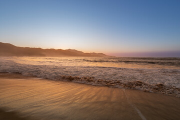 Amanhecer no litoral, sol nascendo atrás da montanha
