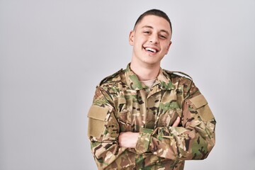 Young man wearing camouflage army uniform happy face smiling with crossed arms looking at the...