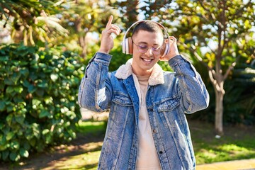 Young hispanic man listening to music and dancing at park