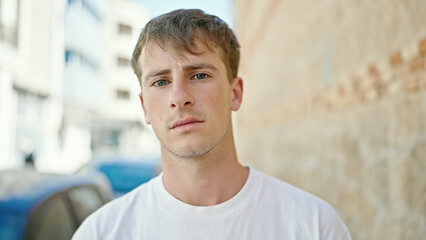 Young caucasian man standing with serious expression at street