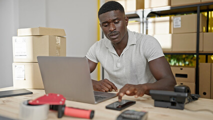 African american man ecommerce business worker using smartphone and laptop at office