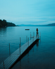Person on a dock on a gloomy blue evening on Lake George in Silver Bay, New York