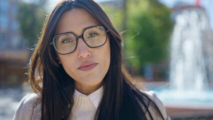 Young beautiful hispanic woman standing with serious expression at park