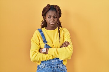 African woman standing over yellow background skeptic and nervous, disapproving expression on face with crossed arms. negative person.