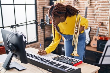 African american woman musician composing song holding trumpet at music studio