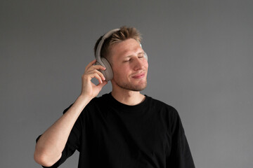 young guy listening to music in wireless headphones at home