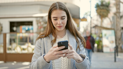 Young hispanic woman using smartphone at coffee shop terrace