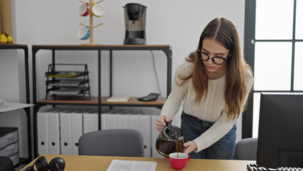 Young hispanic woman business worker pouring coffee on cup at office