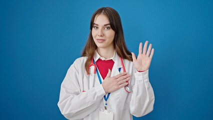 Young hispanic woman doctor making an oath with hand on chest over isolated blue background