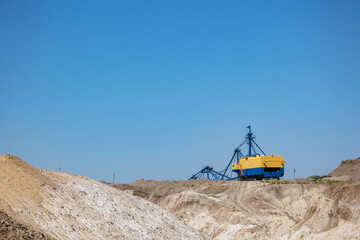 Quarry extraction porcelain clay(kaolin) and quartz sand in the open pit mine. Powerful industrial walking excavator on the site.