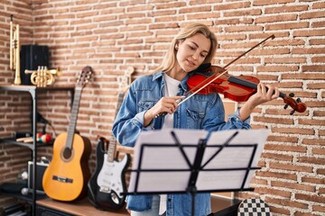 Young blonde woman musician playing violin at music studio © Krakenimages.com