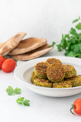 Falafel balls with pita bread, tomatoes and parsley on white background with copy space. Vegetarian healthy food side view