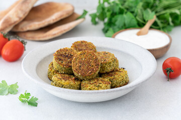 Falafel balls with yogurt sauce, pita bread, tomatoes and parsley on white background with copy space. Vegetarian healthy food side view