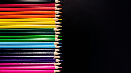 Black background with lots of colorful pencils. School supplies are laid out on a black background - top view. Back to school.