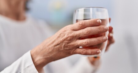 Middle age woman holding glass of tea at home