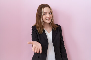 Young caucasian business woman wearing black jacket smiling cheerful offering palm hand giving assistance and acceptance.