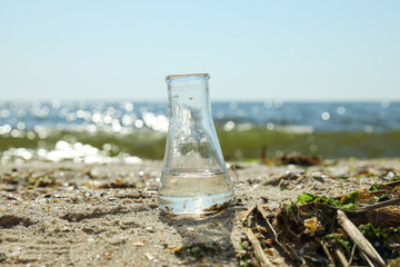 A test tube with contaminated water is standing on the bank of the river