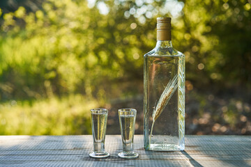 Two shots of crystal clear delicious polish vodka in vintage shoot glasses and rustic style bottle...