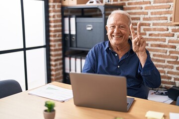 Senior man with grey hair working using computer laptop at the office smiling with happy face...
