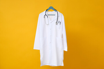 A doctor's white coat with a stethoscope on a yellow background